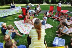 Auf der Picknick-Decke liest die Vorleserin, Melanie Kriegel von Rheinbach Liest e.V., bei strahlenden Sonnenschein den anwesenden Kindern vor.