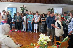 Lesung einer Schulklasse im Seniorenheim mit zahlreichen Senioren als Publikum.