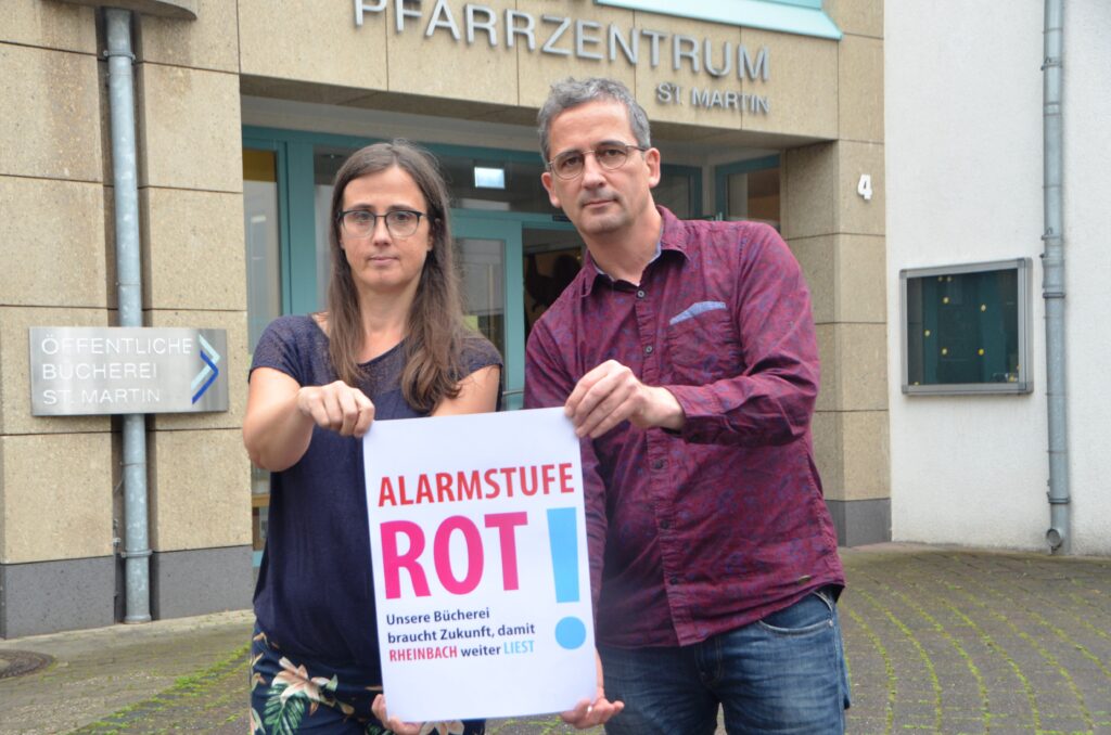 Monika Flieger und Gerd Engel mit einem Plakat zur Aktion vor dem Gebäude der Öffentlichen Bücherei.