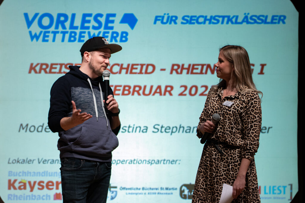 Julius Esser und Christina Stephan stehen sich auf der Bühne gegenüber und moderieren den nächsten Programmpunkt an.