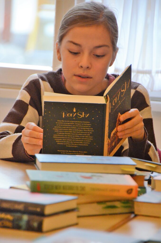 Kreissiegerin Jule Liess aus Rheinbach liest ein Buch in der Hand halten zur Vorbereitung auf den Wettbewerb.