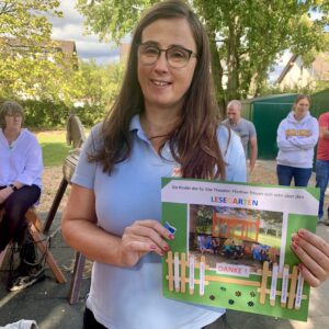 Monika Flieger mit dem selbstgebastelte Dankeschön der Kinder - einem Foto mit den Kindern vor dem Pavilion