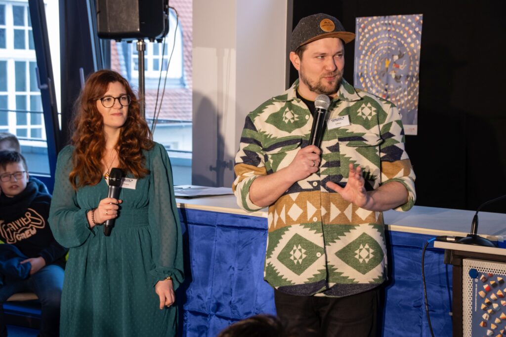 Chiara Jung und Julias Esser das Moderationsduo mit Mikrofonen in der Hand vor der Bühne