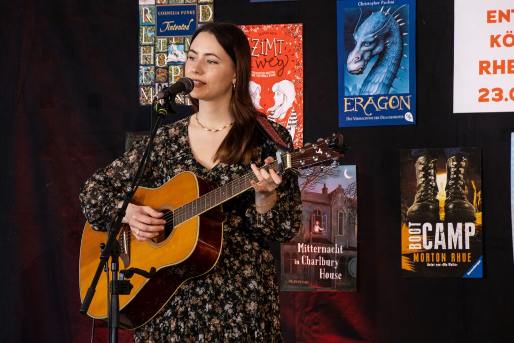 Singer Songwriterin Annalena Sybon singend mit der Gitarre auf der Bühne.