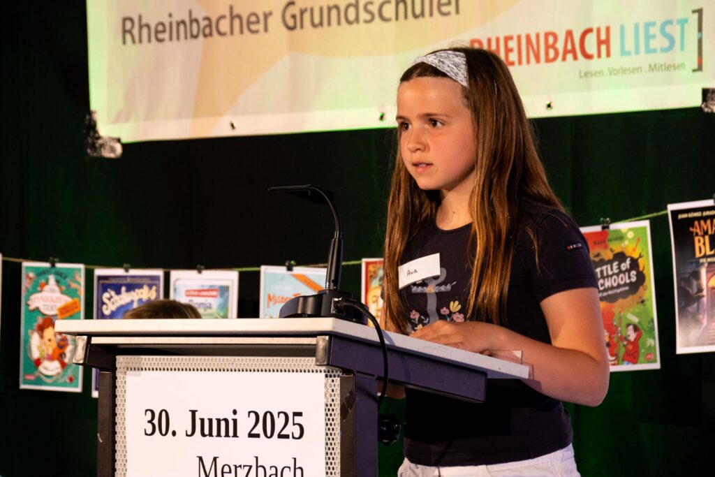 Ava liest aus dem Buch Ronja Räubertochter am Rednerpult vor.