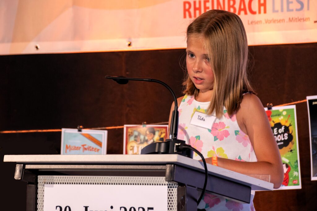 Tilda liest am Rednerpult aus Ihrem Buch "Im Bann der Elemente".