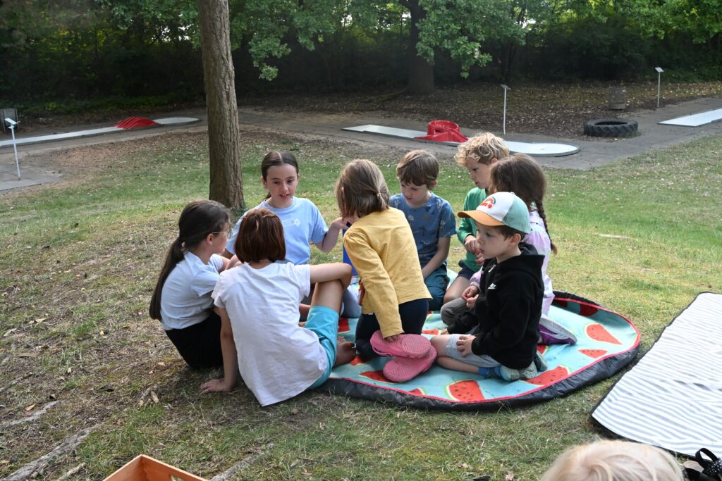 Marie liet einer Gruppe interessierter Kinder auf der Wiese vor.